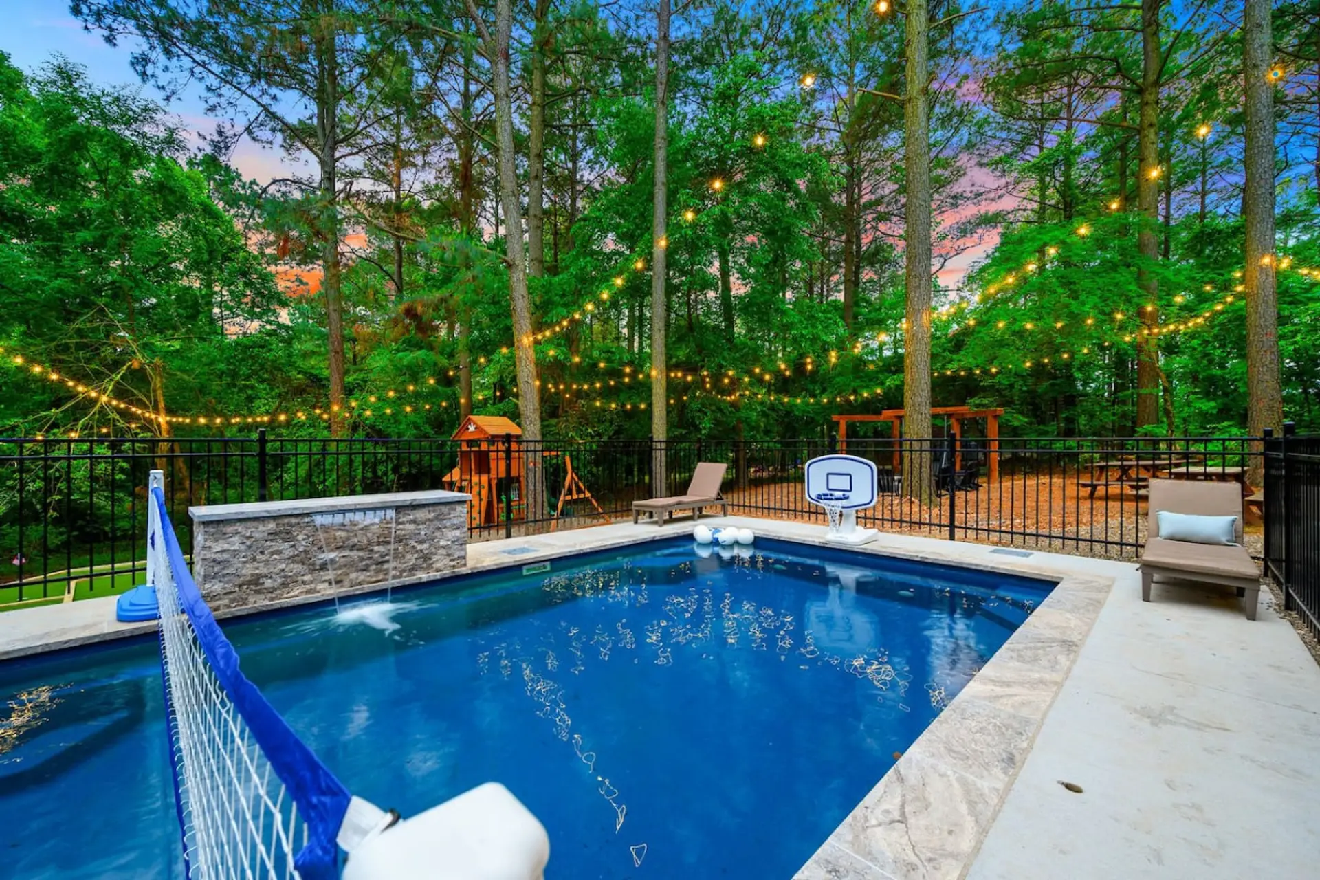 This backyard basically has everything you'd want to hang out and actually use—a pool, basketball hoop, playground for the kids, and string lights that make even a random Tuesday night feel special.