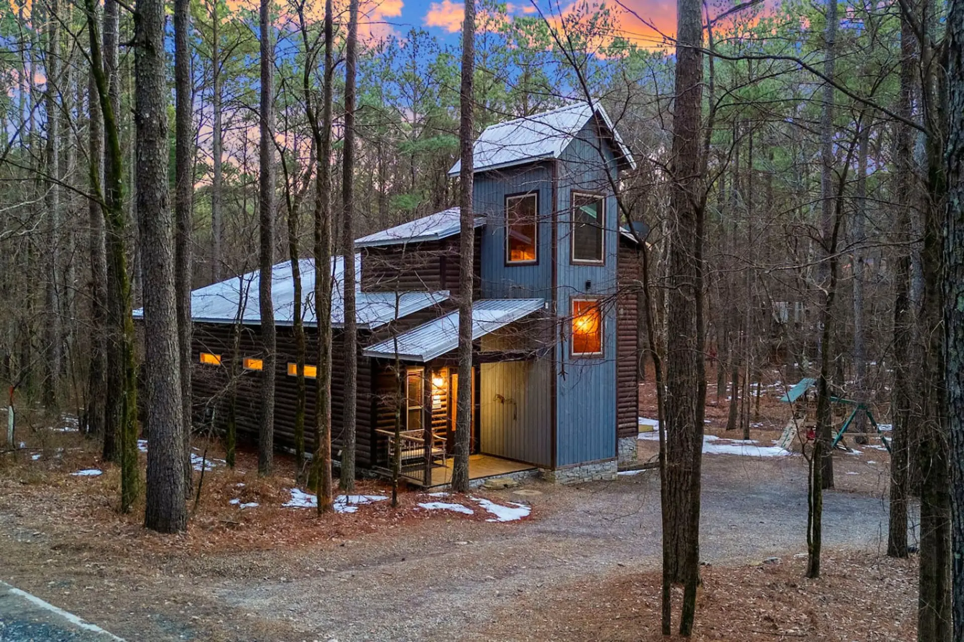 Cozy modern cabin nestled in the woods with warm glowing windows and a covered porch for those peaceful forest mornings.