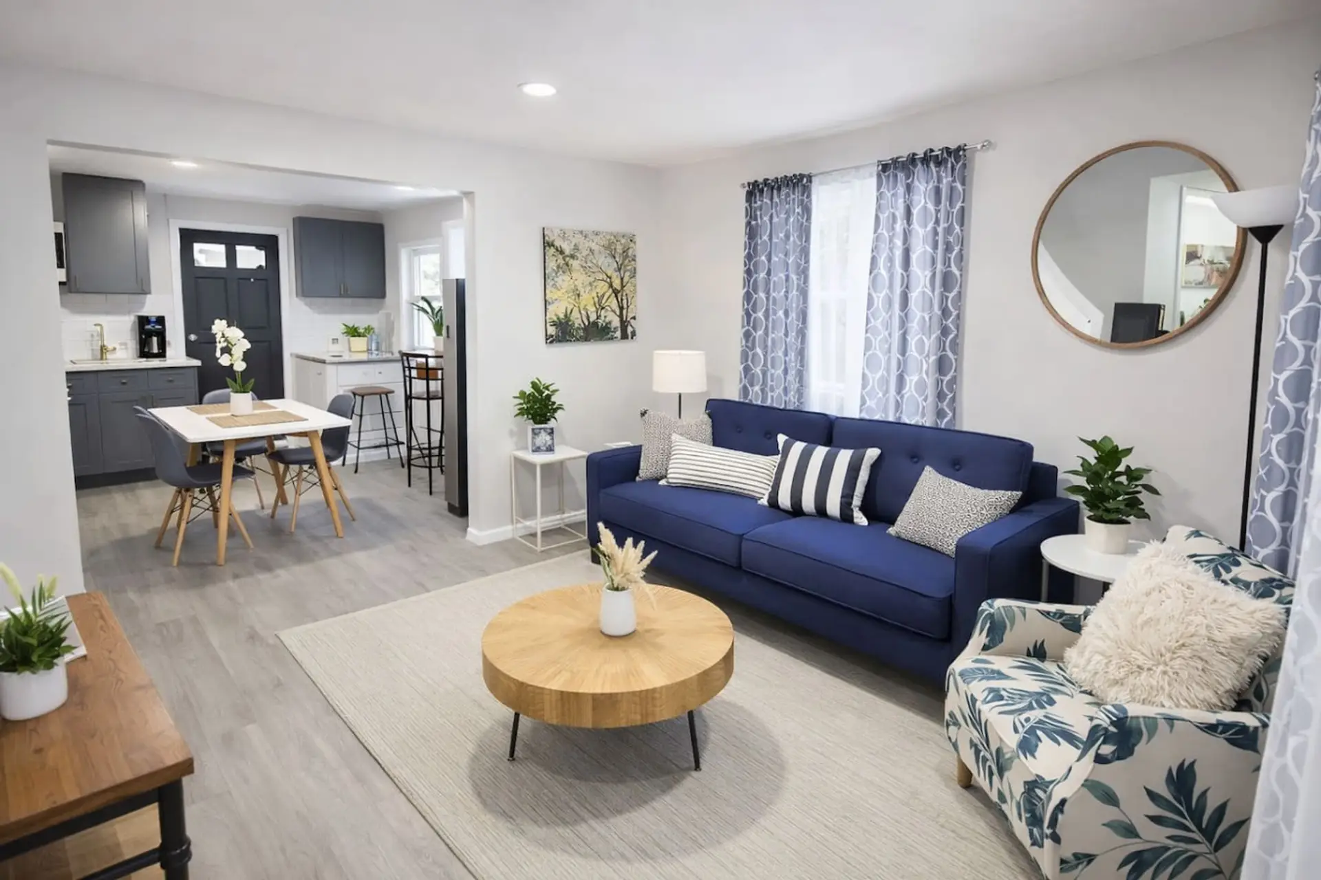 This bright, open-concept living area offers a stylish blue sofa and smart TV, perfectly positioned just steps away from the dining table and fully equipped kitchen.