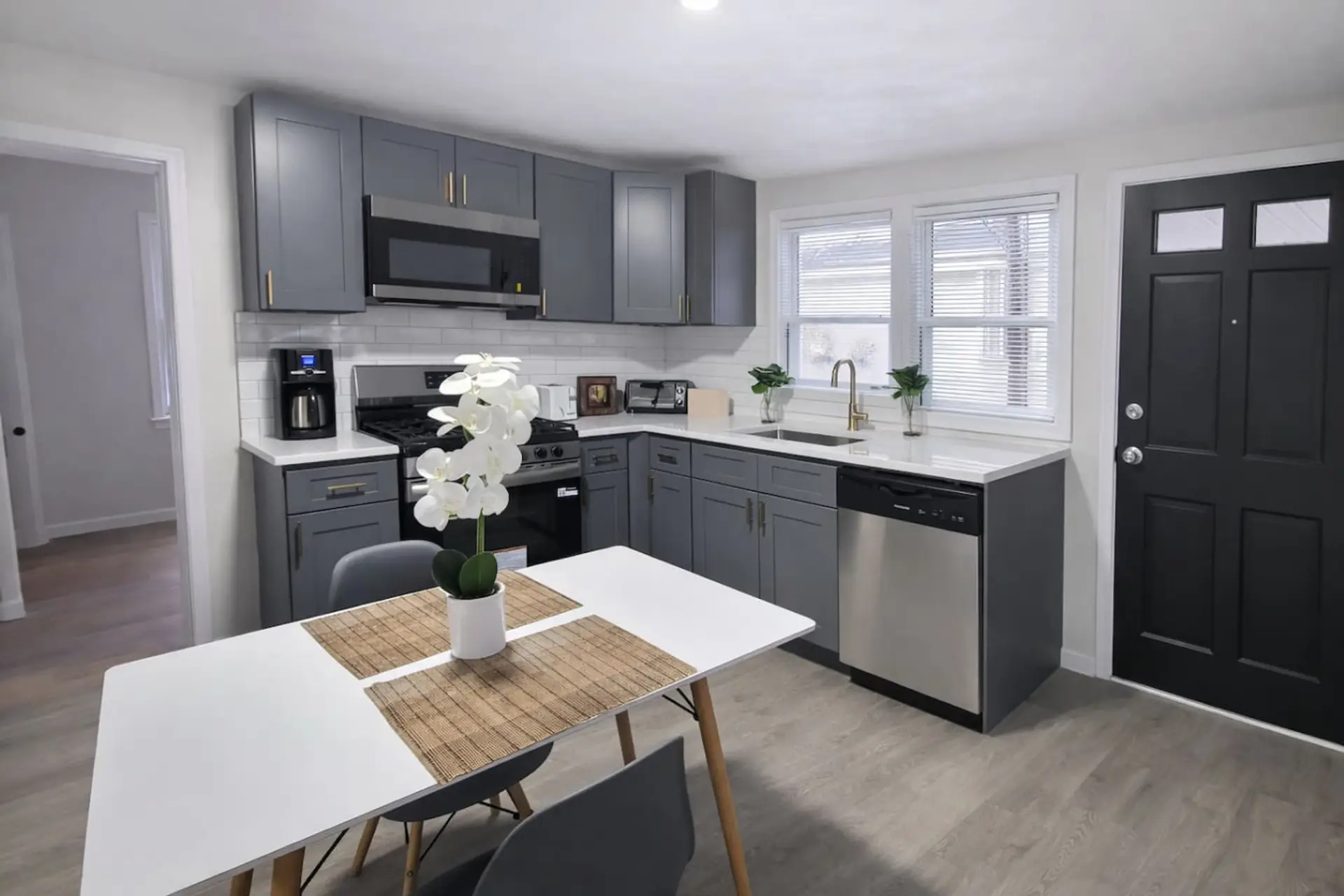 This modern, fully equipped kitchen features sleek gray cabinetry and stainless steel appliances, complete with a cozy breakfast bistro set perfect for enjoying your morning coffee or tea.