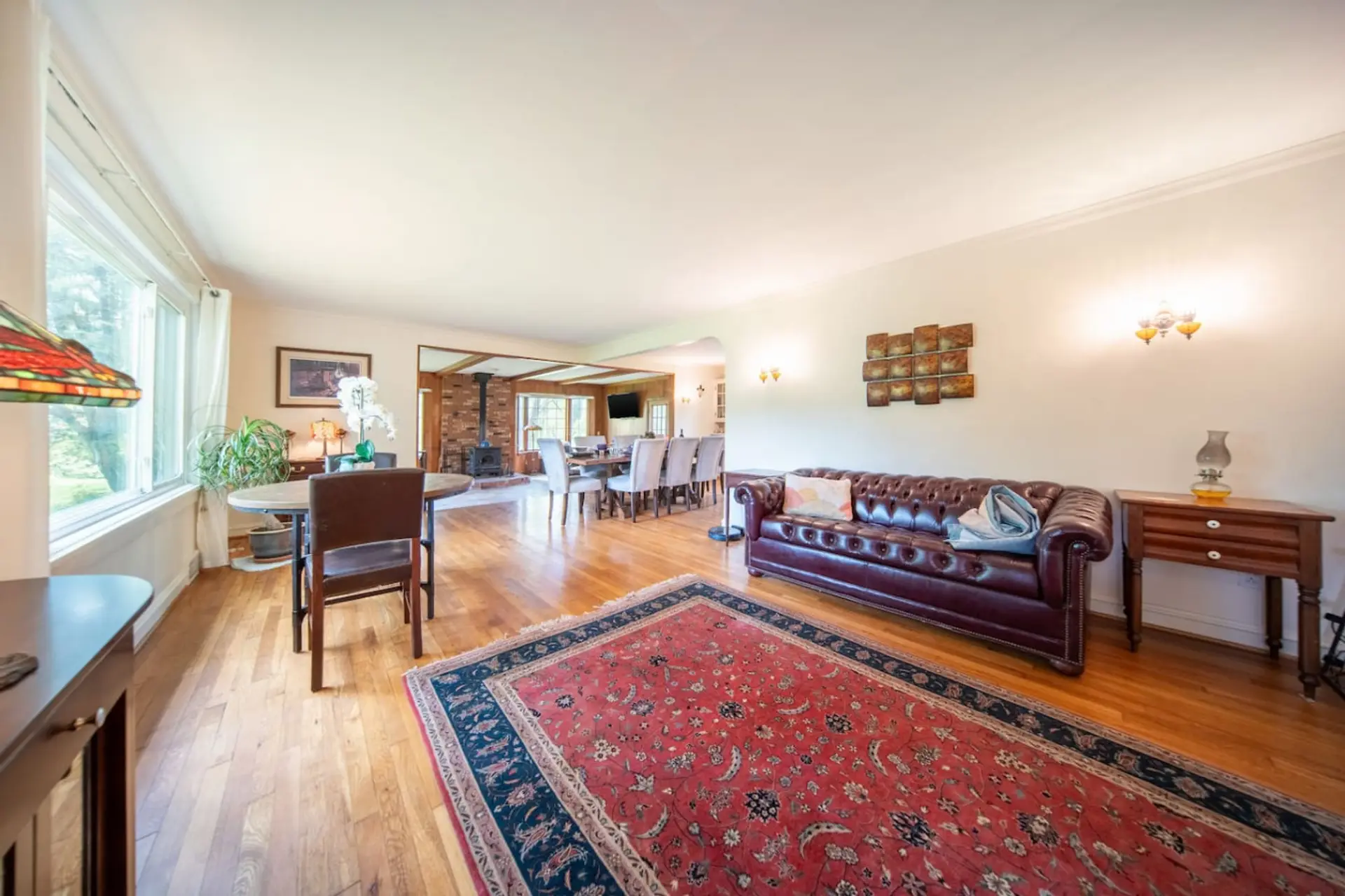 Relax in this spacious and sun-filled living room, featuring modern gray tones, comfortable seating, and a large wall-mounted mirror that enhances the bright, airy feel.