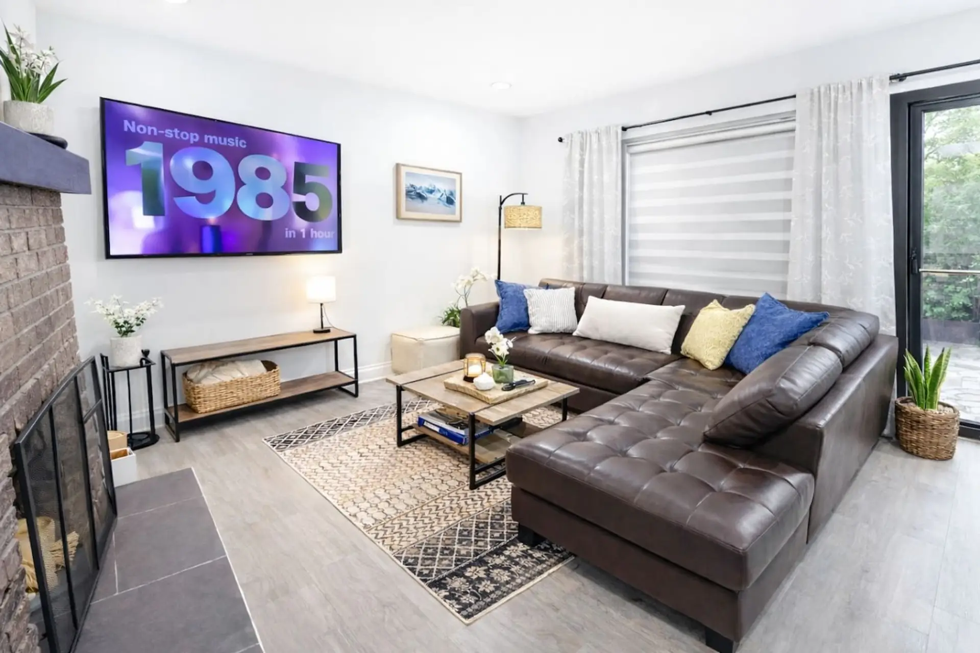 Unwind in the spacious, sun-drenched living area featuring an oversized tufted leather sectional, a massive wall-mounted Smart TV for all your streaming needs, and custom window treatments that allow you to easily transition from a bright, airy works