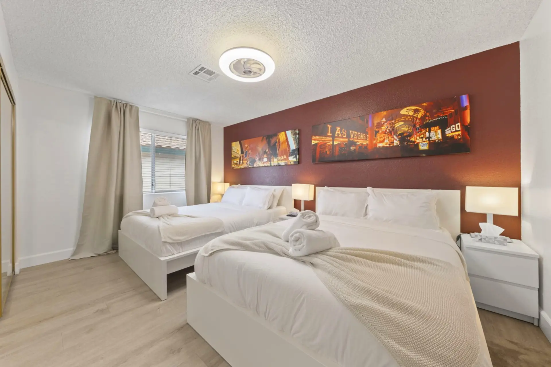 This cozy bedroom features two comfortable beds with fresh white linens, a wall-mounted TV, and stylish decor, creating a relaxing space for your stay in the heart of Las Vegas.