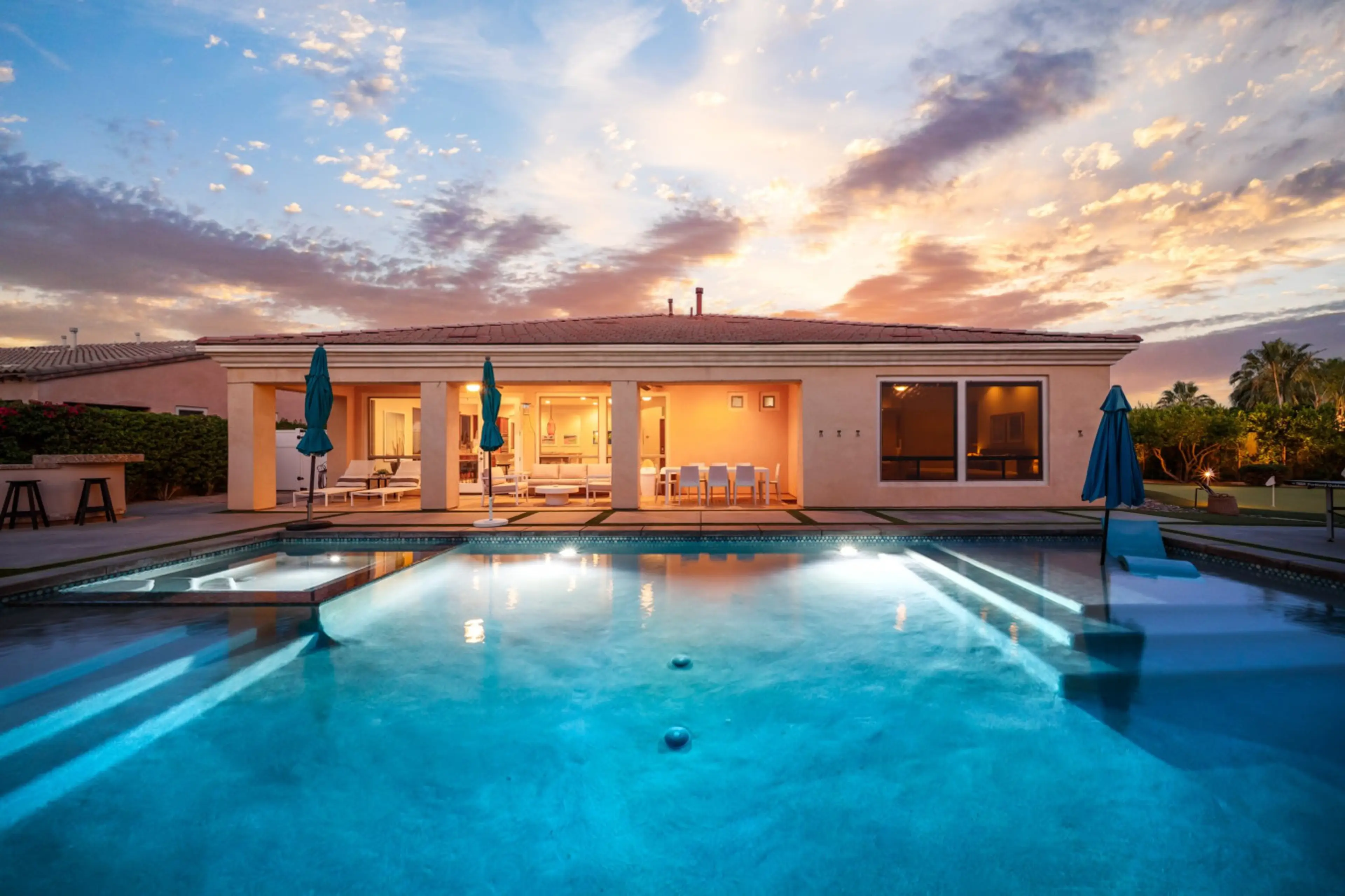 Evening view of a cozy backyard with a glowing pool, perfect for winding down as the sun sets.