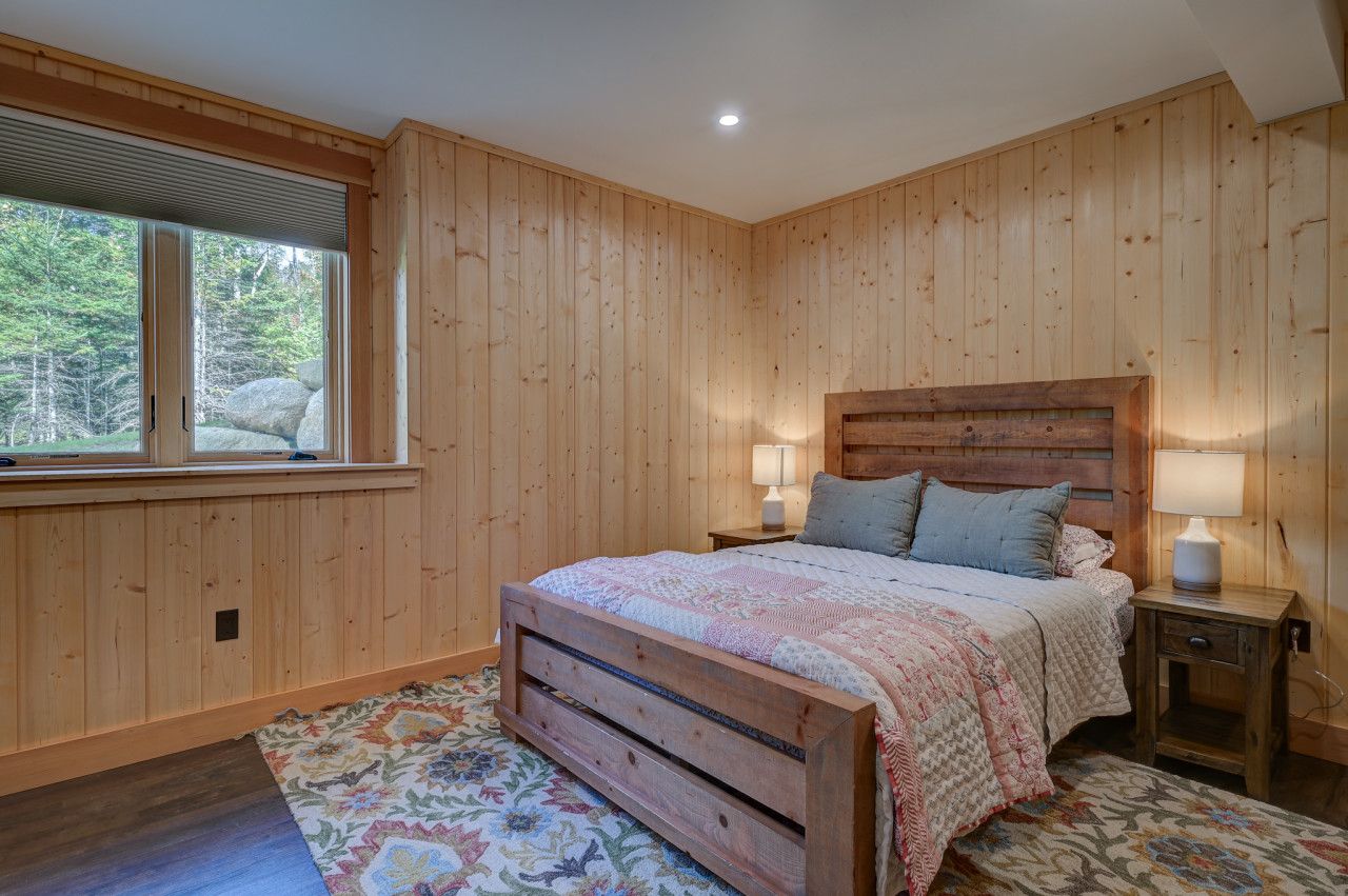 A cozy basement bedroom with a queen bed and four built-in twin bunks, perfect for families or groups.