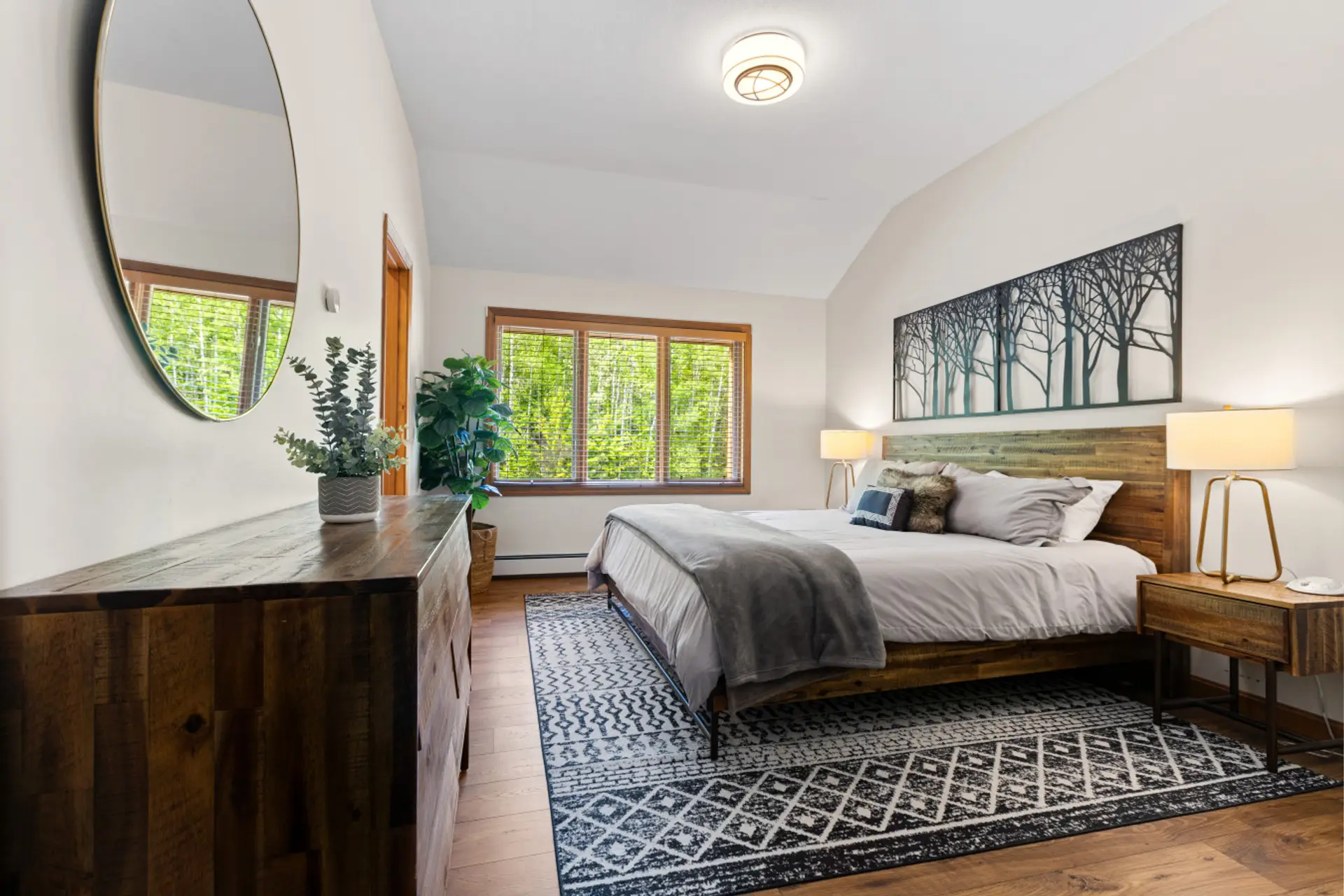 Peaceful ensuite with a king bed, forest views, cozy linens, rustic decor, and private bath—perfect for rest and relaxation.