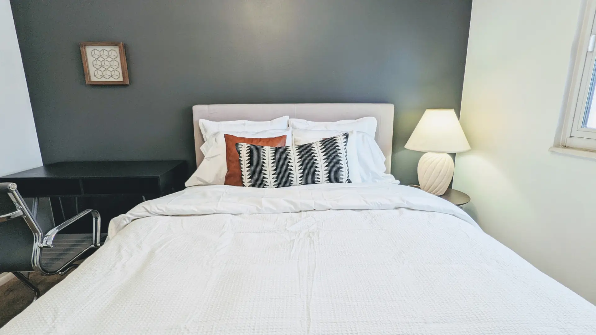 Relax in this private bedroom featuring a comfortable queen-size bed, a dedicated workspace, and a spacious closet for all your storage needs.