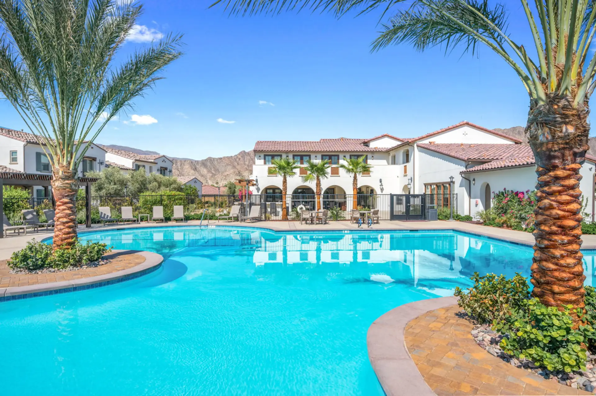 Resort-style pool w/ palm trees & lounge seating, perfect for sunny days by the water