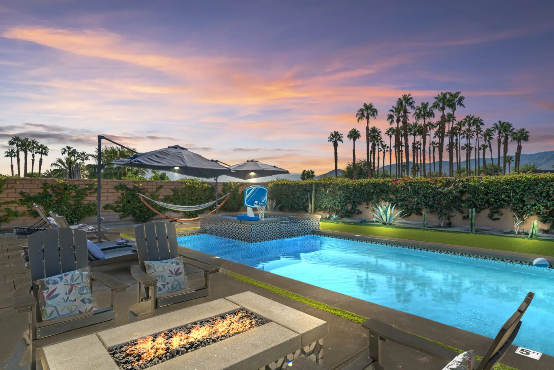 Sunset over the sparkling pool & spa framed by palms, perfect for evening swims under colorful skies