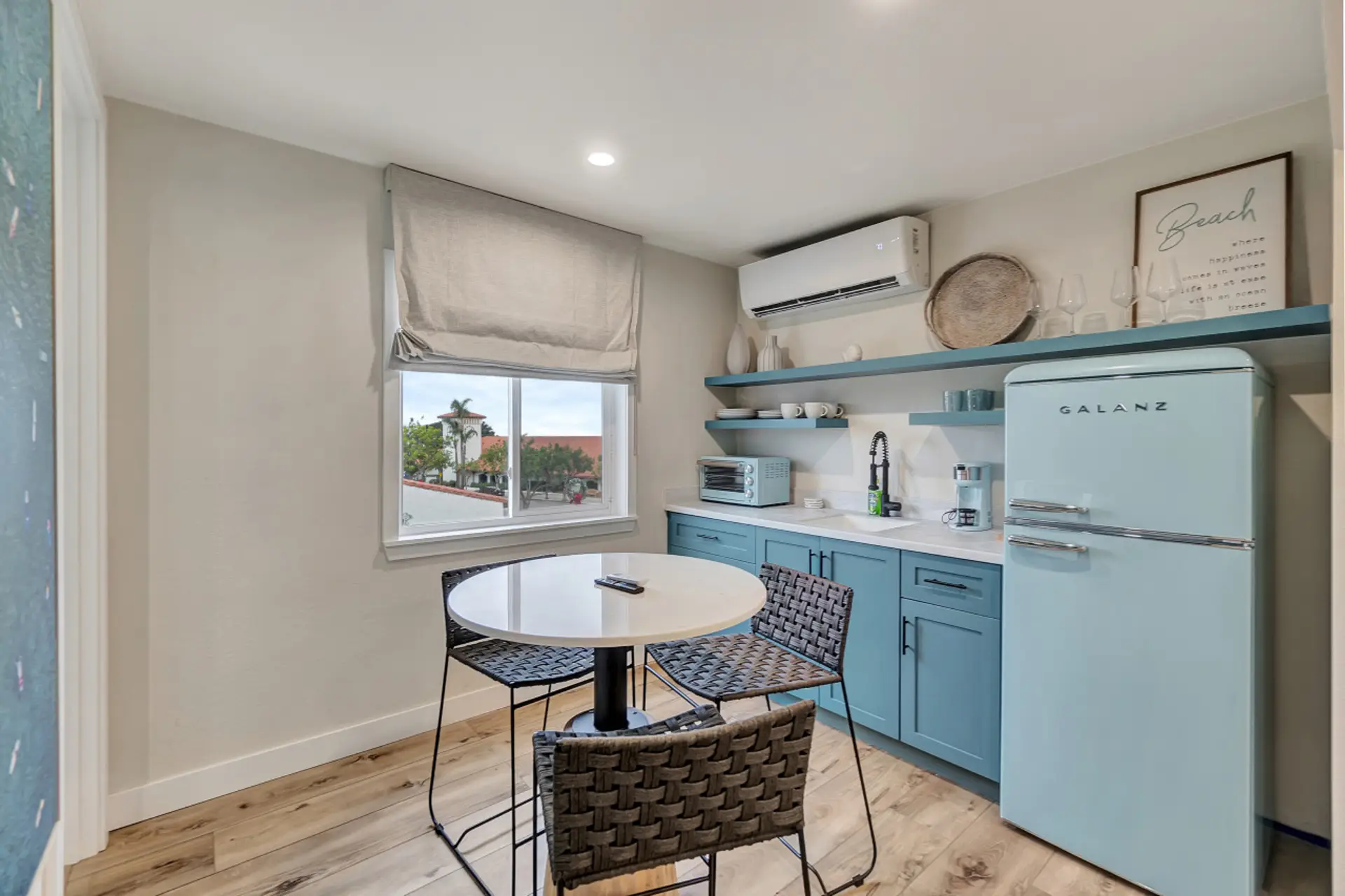 Charming kitchenette w/ retro-style fridge, open shelving & a sunny dining nook by the window