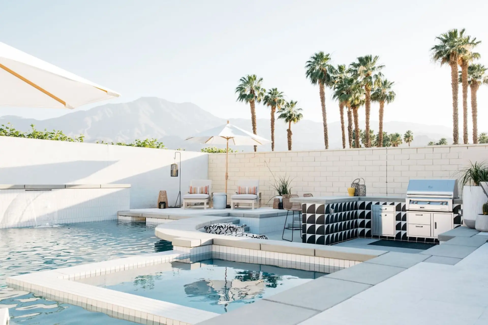 Sunlit pool deck w/ loungers, palms & mountain views for a laid-back day outside