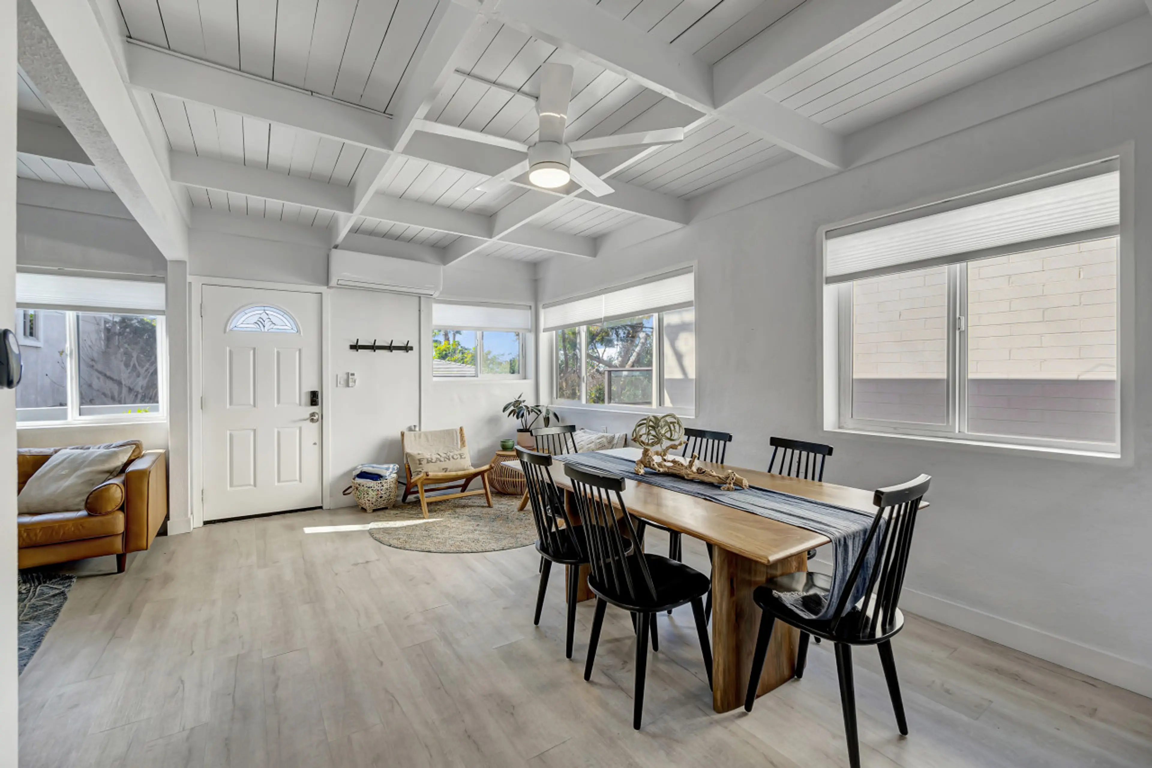 Open-concept dining area w/ long table flowing seamlessly into the airy living room.