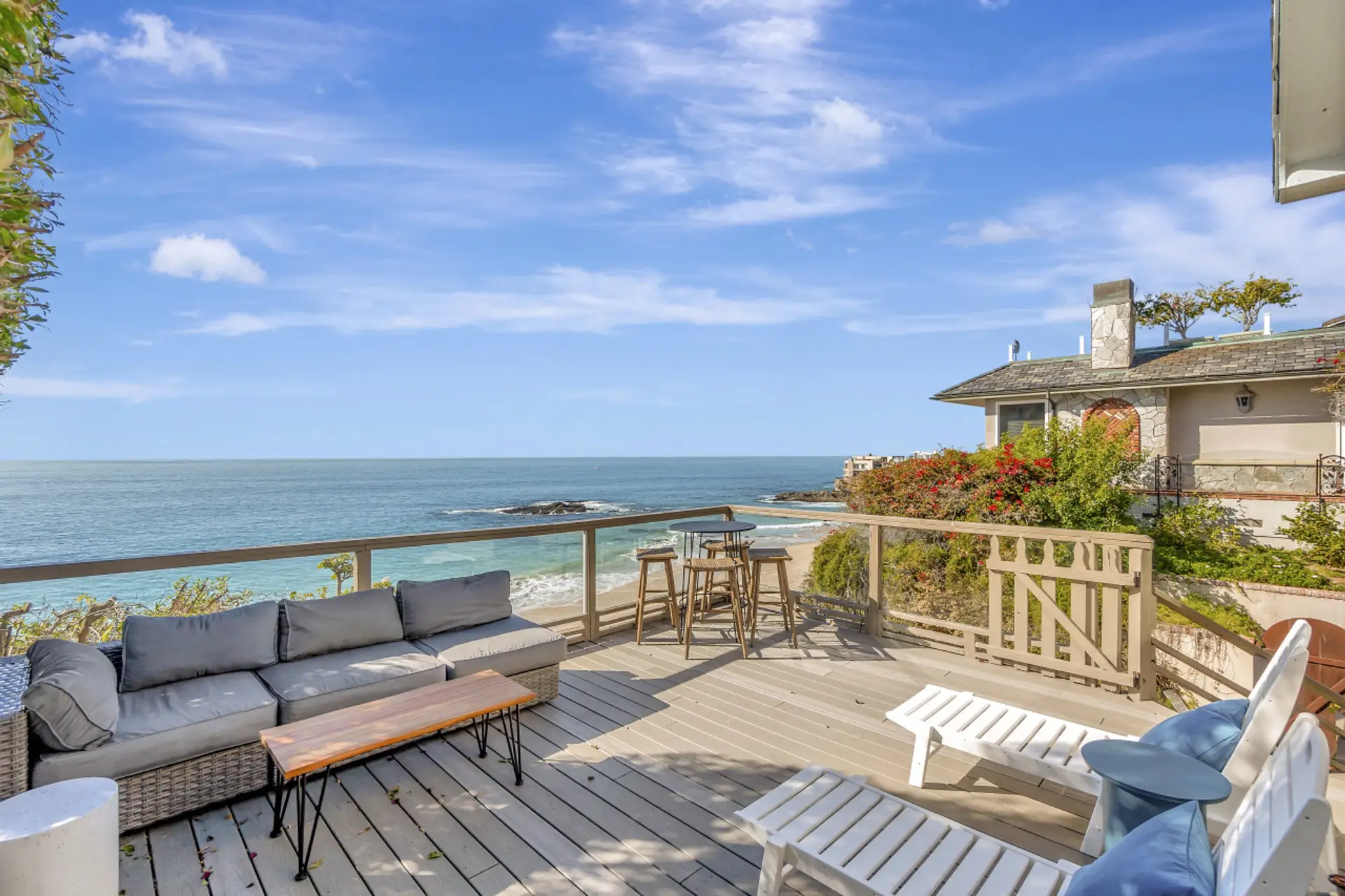 Oceanfront deck w/ lounge seating & blooming flowers, perfect for soaking up sun & sea breezes
