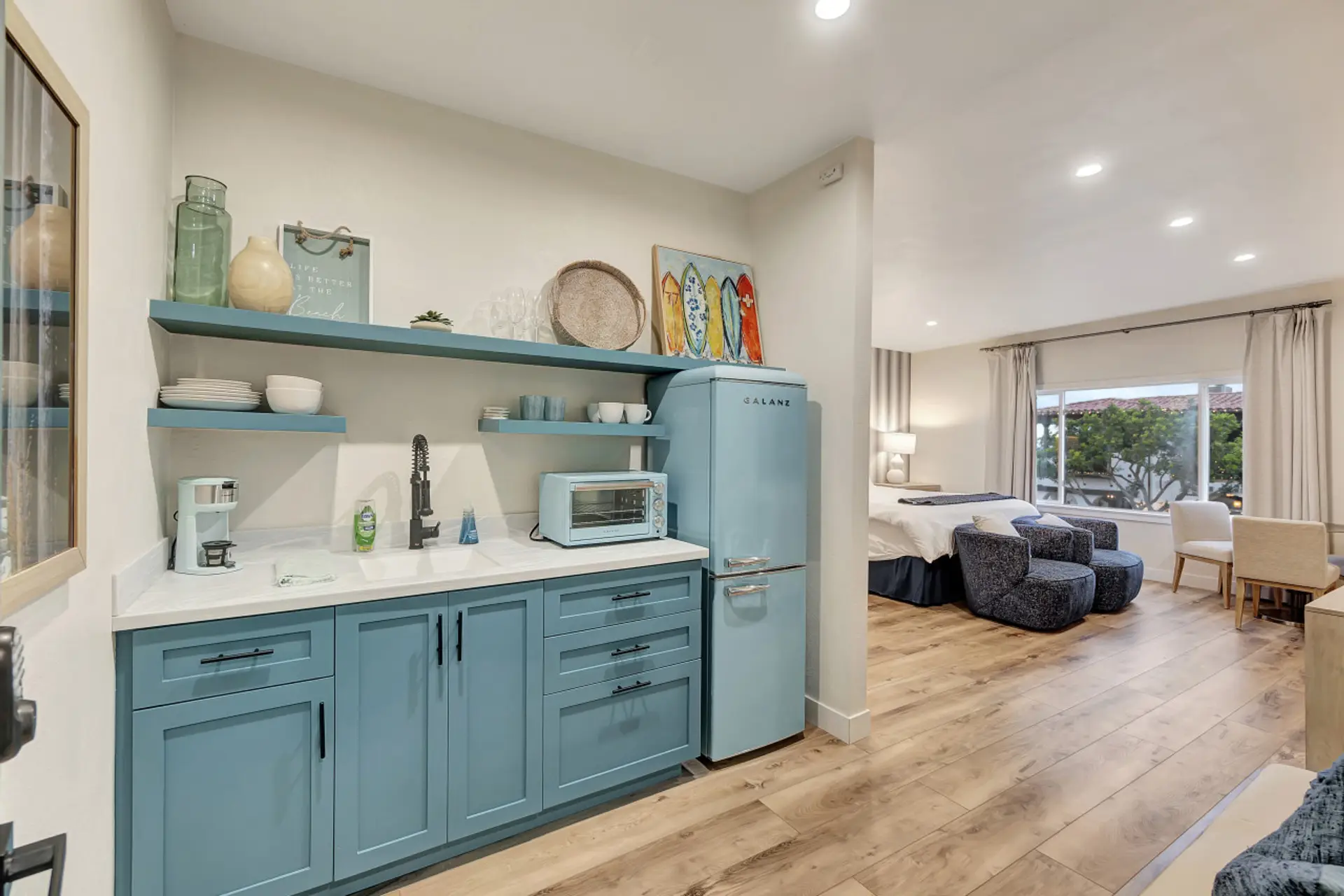 Stylish kitchenette w/ blue cabinetry, open shelves & modern finishes
