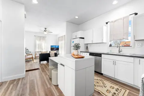 View past the kitchen island to the living room and its ceiling fan