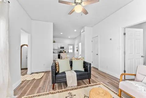 Living room with a leather sofa and armchairs, open to the kitchen beyond