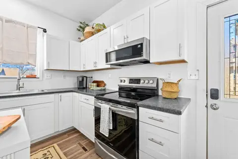 Kitchen with a stainless range, white cabinets, and a side door