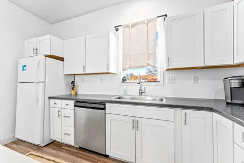 Kitchen sink under a window, with a dishwasher and a white fridge