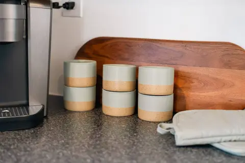 Coffee maker, mugs, and a cutting board on the counter