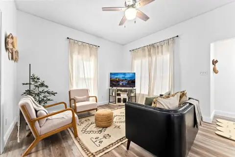 Living room with two wood-frame armchairs, a leather sofa, and a patterned rug
