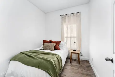 Bedroom with a queen bed, a green throw, and a side table by the window