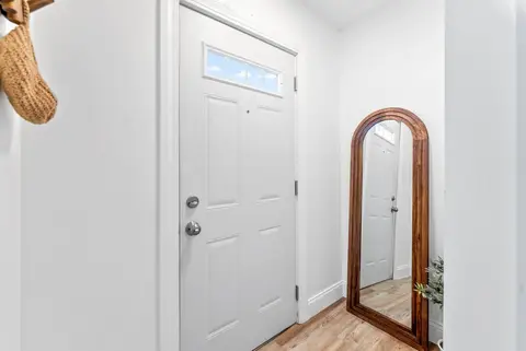 Entry with a white front door and a tall arched mirror