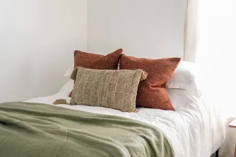 Queen bed with rust and green pillows and a green throw