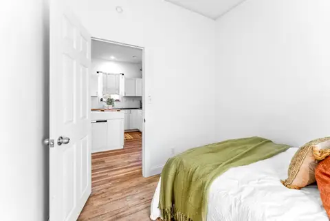 Queen bed with a view through the door to the kitchen