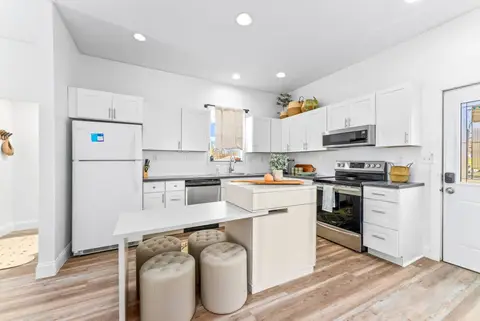 Kitchen island with round stools, facing the range and white cabinets