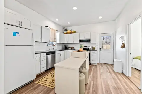 Kitchen with white cabinets, a white fridge, and an island with round stools