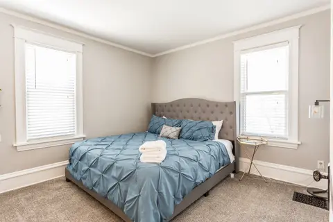 Bedroom with a queen bed, a gray tufted headboard, and blue bedding