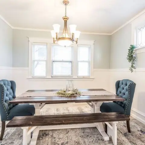 Dining area with a farmhouse table, blue tufted chairs, and a chandelier