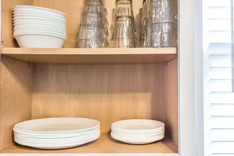 Shelves stacked with plates, bowls, and drinking glasses