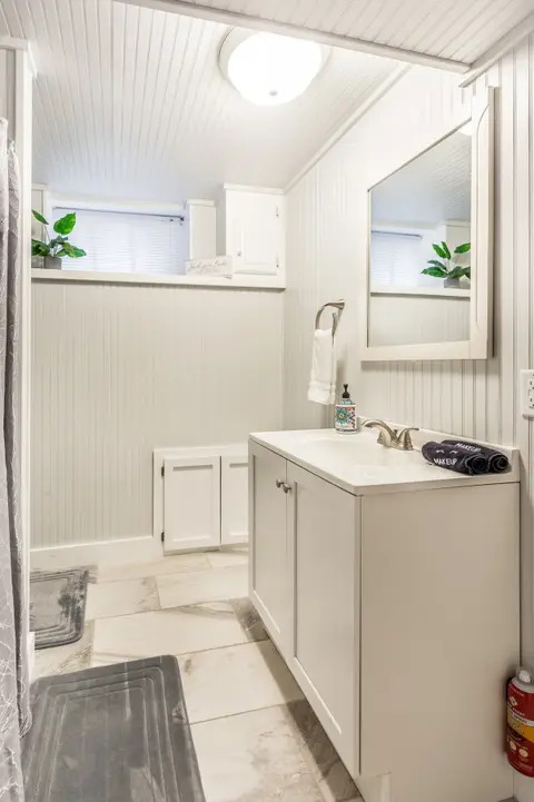 Bathroom with beadboard walls, a white vanity, and a shower curtain