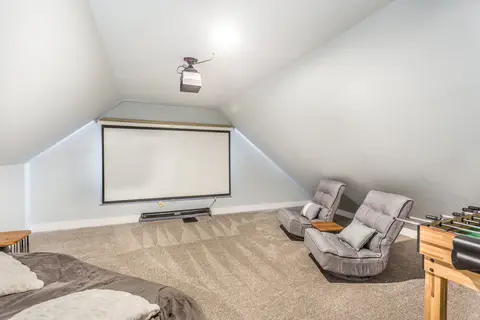 Attic movie room with a projector screen, floor chairs, and a foosball table