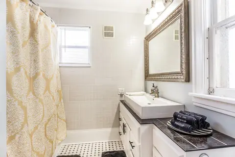 Bathroom with a tiled tub and shower, a framed mirror, and a long vanity