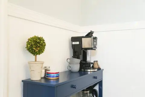Coffee station with a coffee maker and mugs on a navy cabinet