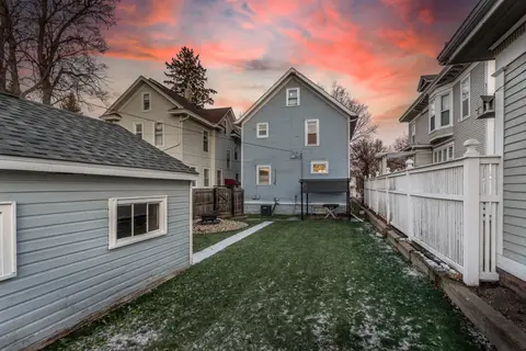 Fenced backyard at sunset, with a fire pit by the back gate