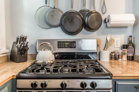 Gas range with hanging pans, a knife block, and a kettle