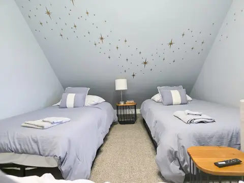 Two twin beds under a sloped ceiling painted with gold stars