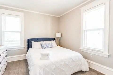 Bedroom with a queen bed, a navy headboard, and white bedding