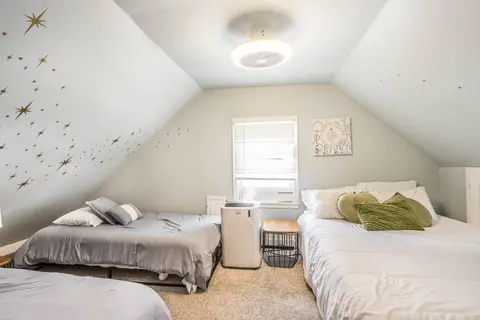 Attic bedroom with two twin beds and a queen bed beneath star decals