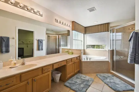 Primary bathroom with a long vanity, a corner tub, and a glass shower