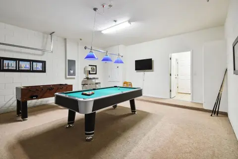 Game room with a pool table, foosball, and a wall-mounted TV