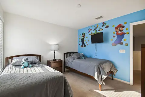 Twin bed beside a blue accent wall with a wall-mounted TV