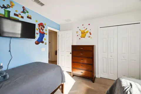 Twin bedroom with a blue accent wall, video game decals, and a TV