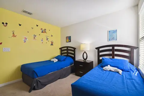 Two twin beds with blue bedding and character wall decals