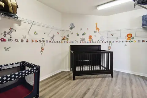 Nursery with a crib, a Pack ’n Play, and animal wall decals