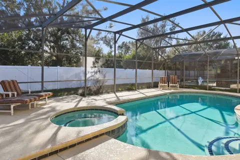 Private pool and hot tub inside a screened enclosure, with loungers