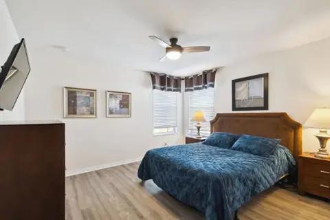 Queen bedroom with blue bedding and a ceiling fan